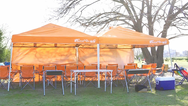 屋外にタープやテーブル、コンロなどBBQ機材が設置されている