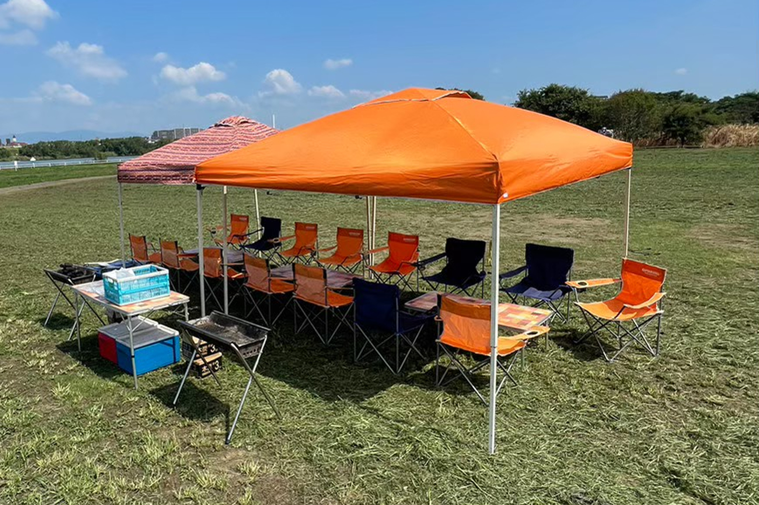 芝生の上にタープが建ててあり、タープの下に椅子やテーブルが並べられている写真